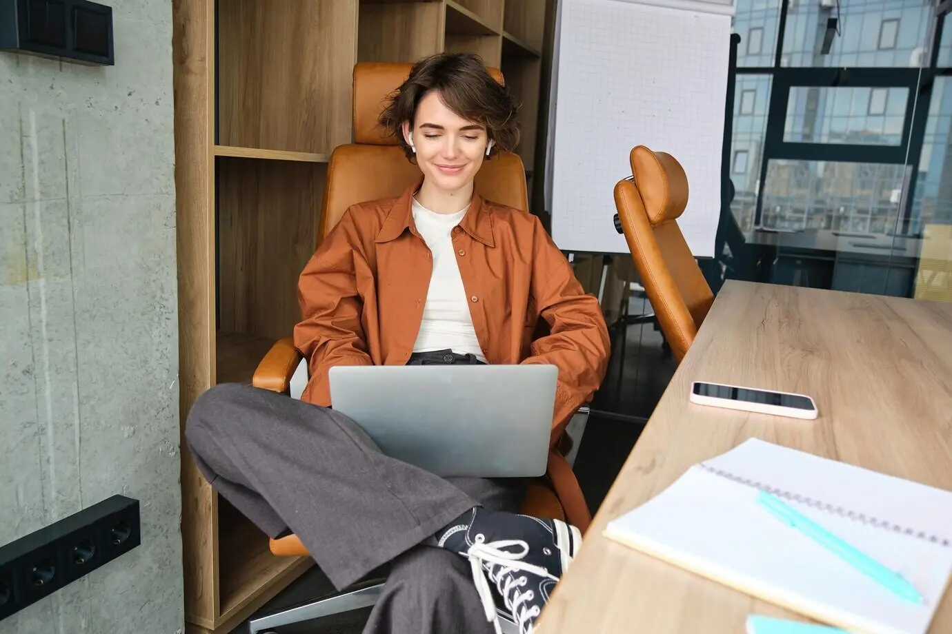 Retrato de una joven gerente, mujer trabajadora, en una oficina, usando un portátil y tecleando en el ordenador.