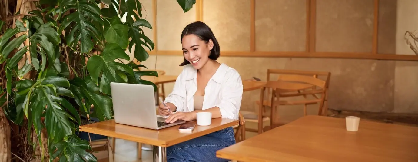 Mujer de negocios elegante con un portátil, sentada en un café y trabajando en el ordenador, gestionando el negocio y